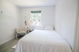 a white bed in a white bedroom with a chair at The Flat a Wanderlust Abodes property in Central Lake