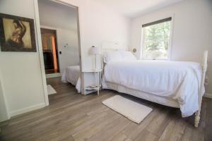 a white bedroom with a bed and a window at The Flat a Wanderlust Abodes property in Central Lake +12 photos