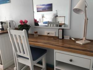 a desk with a mirror and a white chair at BlueSky Arniston Guest House in Arniston