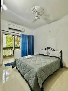 a bedroom with a bed and a blue curtain at Sober 2bhk Pet Friendly Apartment with pool view in Marmagao