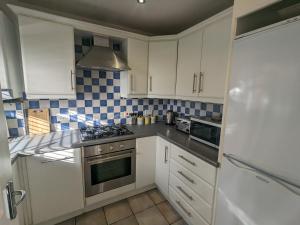 een keuken met witte kasten en een fornuis met oven bij Superb Modern Apartment, FREE Secure Parking! in Allesley