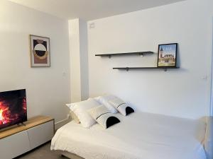 um quarto com uma cama branca e uma televisão em Le Duc de Guise em Calais