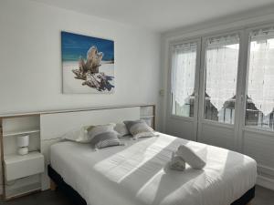 um quarto com uma cama grande com lençóis brancos e almofadas em Le Duc de Guise em Calais