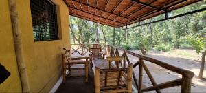 Athulyam Kanha, kanha national park, mukki gate في Khāpa: شرفة مع كراسي وطاولة على المنزل