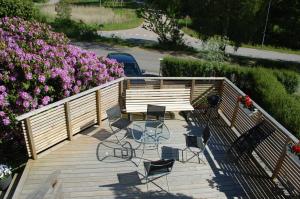 a wooden deck with chairs and pink flowers at Grottstugan in Ljungskile