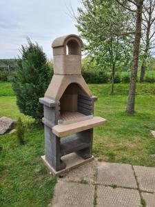 un horno de piedra sentado en un campo de hierba en Namelis sodyboje Lazduona, 