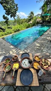 uma mesa com tigelas e pratos de comida ao lado de uma piscina em Villa Hillcrest em Weligama