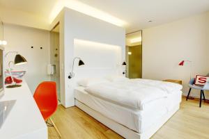 a bedroom with a white bed and a orange chair at Smartcity Designhotel in Hannover