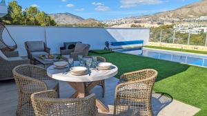 eine Terrasse mit Tisch und Stühlen und einem Pool in der Unterkunft PANORAMIC pool & mountains house in Finestrat