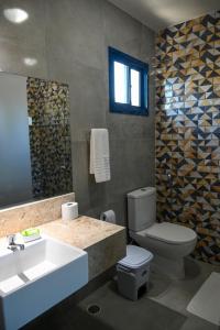 een badkamer met een wastafel, een toilet en een spiegel bij Chalés Casuarinas in Japaratinga