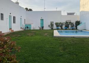 un patio trasero con piscina y un edificio blanco en Alojamiento Rural La Mejora, en Conil de la Frontera