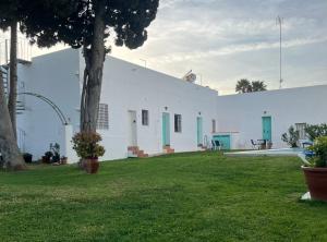 un edificio blanco con puertas verdes y patio en Alojamiento Rural La Mejora, en Conil de la Frontera