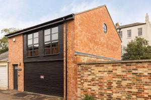 un edificio de ladrillo con una puerta de garaje negra en Pittville Loft Apartment - Central Cheltenham Highly Rated with Free Parking, 