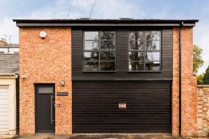 a black garage door on a brick house at Pittville Loft Apartment - Central Cheltenham Highly Rated with Free Parking in Gloucestershire