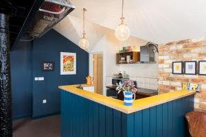 a kitchen with blue walls and a yellow counter at Pittville Loft Apartment - Central Cheltenham Highly Rated with Free Parking in Gloucestershire +20 photos