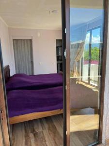 a bedroom with a purple bed and a balcony at TikTok house in K'obulet'i