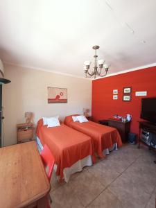 a bedroom with two beds and a red wall at Habitación de huéspedes con entrada independiente in Concordia
