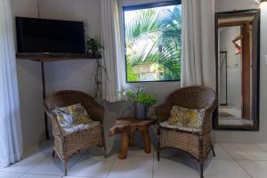 a living room with two chairs and a television at Pousada Villa Mares in Barra Grande