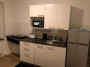 eine Küche mit weißen Schränken, einer Spüle und einer Mikrowelle in der Unterkunft Ferienwohnung am Marienplatz in Görlitz