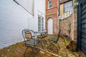 a patio with three chairs and a table and a building at Hanwell House, Long Melford in Long Melford