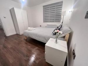 a bedroom with a bed and a table with a vase of flowers at Aylesbury Flat 3 with free Parking in Buckinghamshire