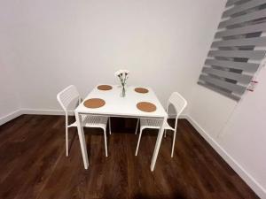 a white table with chairs and a vase of flowers on it at Aylesbury Flat 3 with free Parking in Buckinghamshire