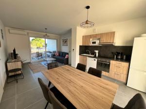a kitchen and living room with a wooden table and chairs at APPT 6 personnes BABORD in Leucate