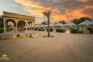 a pavilion with a palm tree in the middle of a resort at Heritage Juma Resort with swimming pool in Jaisalmer