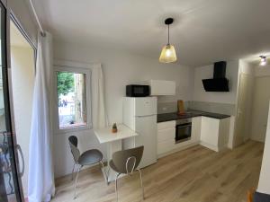 une cuisine avec deux chaises, une table et une fenêtre dans l'établissement Appartement en bord de mer 1, à Banyuls-sur-Mer
