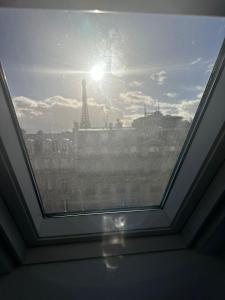 ein Fenster mit Blick auf den Eiffelturm in der Unterkunft Petit studette sous le toit in the heart of the fashion and luxury district in Paris