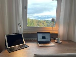 dos ordenadores portátiles sentados en un escritorio frente a una ventana en Villa Talblick im Naturpark Altmühltal en Greding