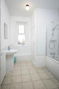 a white bathroom with a tub and a sink at Lytham Place in Blackpool
