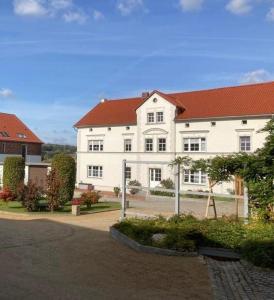 ein großes weißes Gebäude mit rotem Dach in der Unterkunft Ferienwohnung Schöpstalblick in Ebersbach