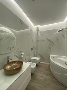 a white bathroom with a sink and a toilet at Riar Apartaments in Korçë