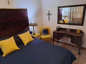 a bedroom with a blue bed with yellow pillows and a mirror at Ellipsis Cottage in Knysna