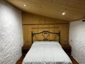 1 dormitorio con 1 cama en una pared de madera en Vivienda turística LA CAPE, en Segura de la Sierra
