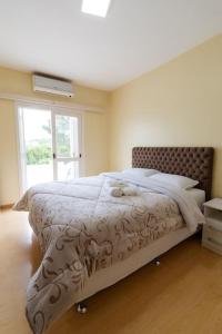 a bedroom with a bed with a white comforter and a window at Casa para 6 pessoas in Bento Gonçalves