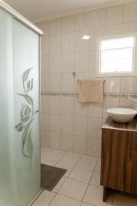 a bathroom with a sink and a glass shower at Casa para 6 pessoas in Bento Gonçalves