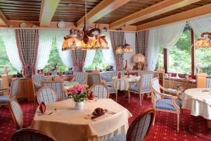 a restaurant with tables and chairs and a chandelier at Wellness und Romantik Hotel Landhaus Helmboldt Helmboldt in Bad Sachsa