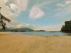 a sandy beach with a pier in the water at Condomínio Fazenda Garatucaia in Angra dos Reis