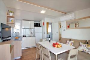 a kitchen and living room with a table with a bowl of fruit at Škrila Sunny Camping by Valamar in Punat