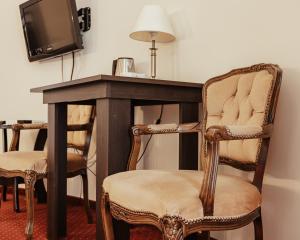 a room with a desk with two chairs and a tv at Hotel Korona in Rybnik
