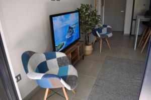 a living room with two chairs and a flat screen tv at Dpto Pucón, camino al volcán in Pucón