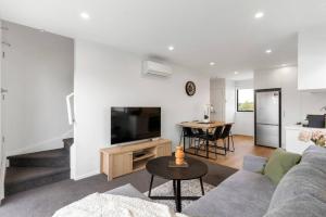 sala de estar con sofá, TV y mesa en Contemporary Urban Retreat, en Auckland