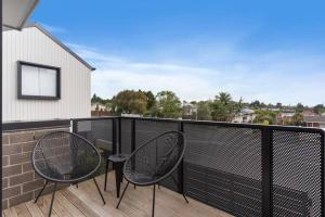 a balcony with two chairs and a fence at Contemporary Urban Retreat in Auckland