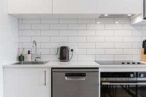 cocina blanca con fregadero y fogones en Contemporary Urban Retreat, en Auckland
