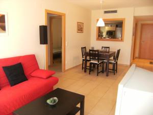 a living room with a red couch and a table at Apartamentos Athenea in Ampurias