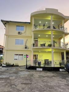 a yellow building with balconies and tables in a parking lot at Sky Inn Hotel in Freetown