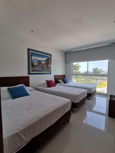 a bedroom with three beds and a large window at Karibana Espectacular in Cartagena de Indias