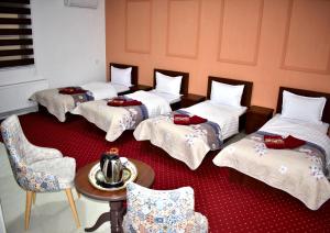 três camas num quarto com uma mesa e cadeiras em Hotel Shodlik em Samarkand